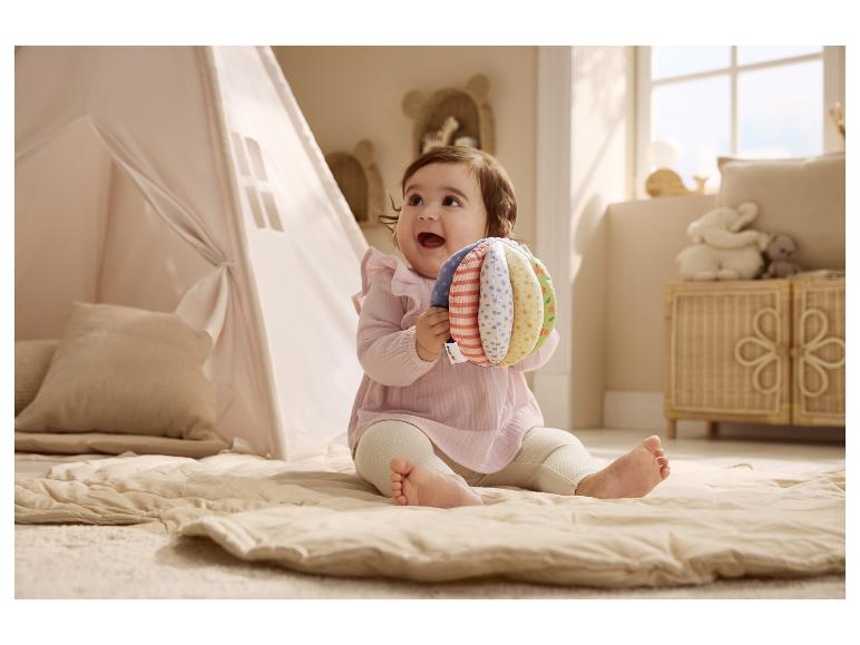 Baby zittend op een kleed spelend met een pluche bal van LUPILU®.