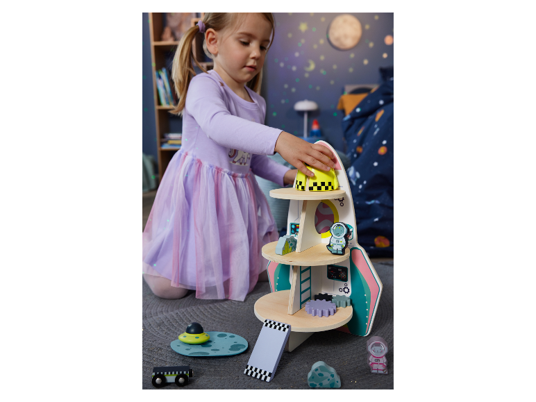 Een meisje speelt met een houten raket speelgoed.