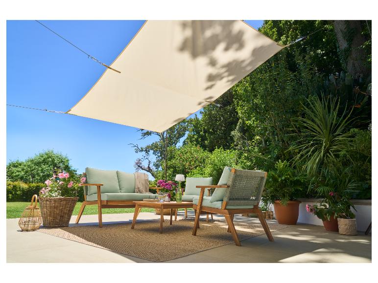 Tuinmeubelset met bank, fauteuils, salontafel en schaduwdoek op een terras.