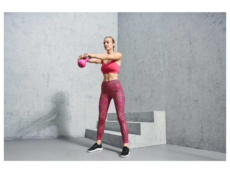 Een vrouw in roze sportbeha en luipaardprint leggings met roze gewichtheffer