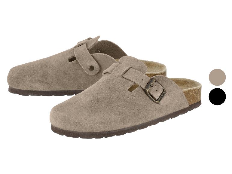 Twee beige suède klompen met gespen, de ene voor de andere.