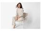 Vrouw in beige loungewear zit op een beige fauteuil.