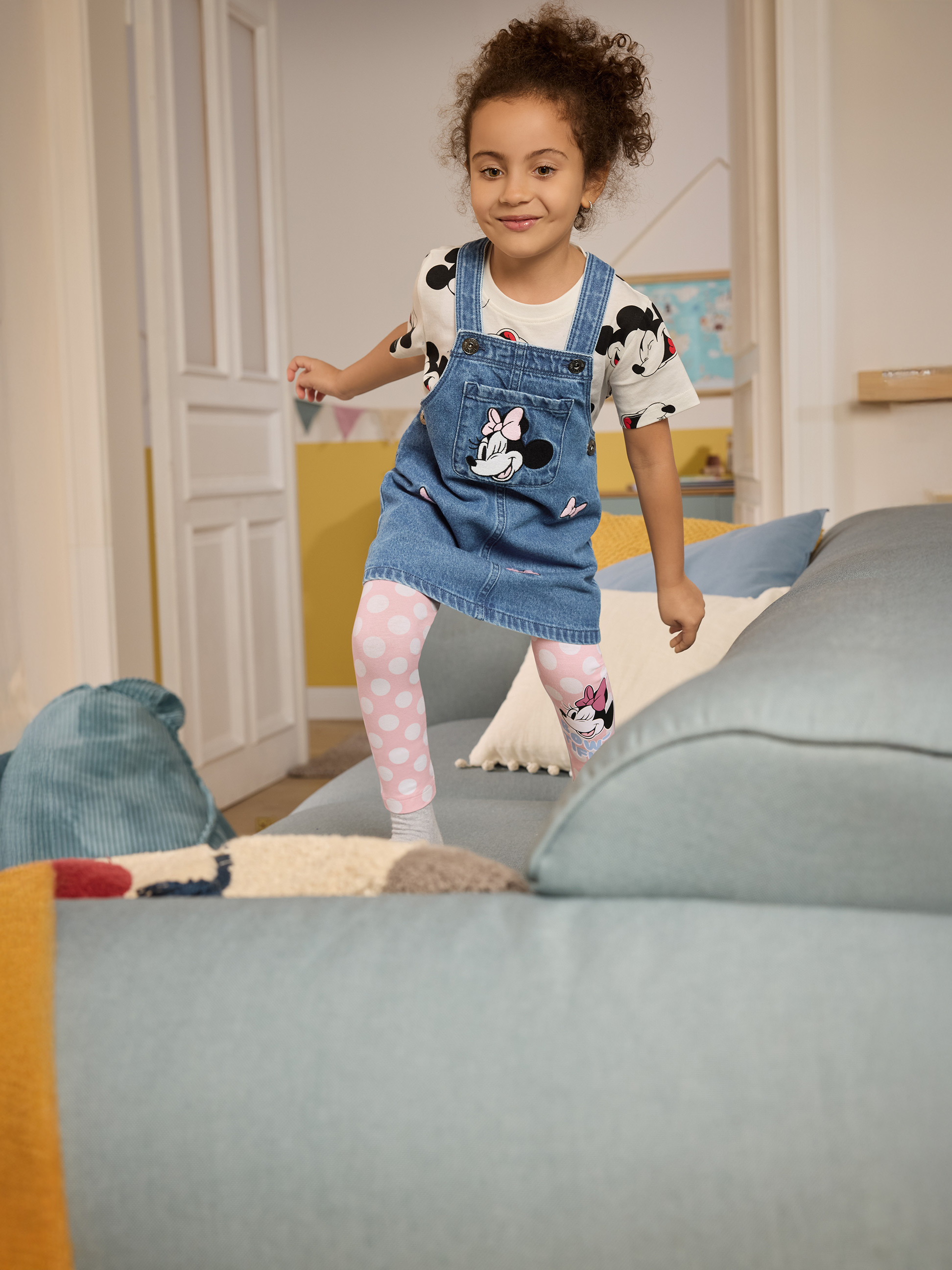Meisje in denim salopette met Minnie Mouse en roze stippenlegging