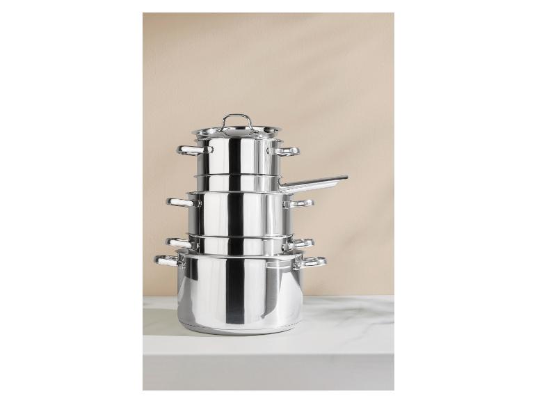 Gestapelde roestvrijstalen pannen op een wit aanrecht.