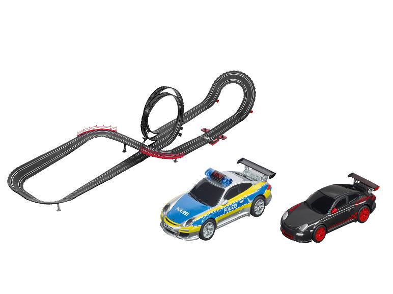 Een Carrera-racebaan met een blauwe politie-Porsche en een zwarte Porsche.