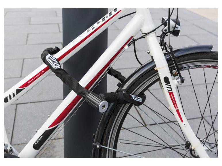 Witte fiets met een zwart kettingslot, met de tekst 'PREMIUM LIGHTWEIGHT ALLOY' en 'TREKKING LITE SERIES'.