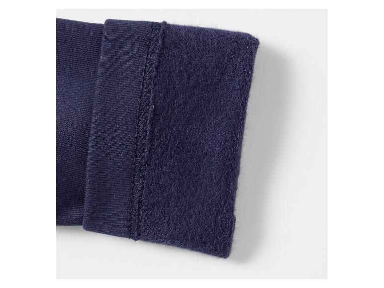 Close-up van donkerblauw gebreid en fleecemateriaal, verbonden door een naad.