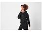 Vrouw in een zwarte hoodie met rits en bijpassende joggingbroek.