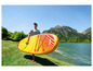Een man draagt een gele Aqua Marina Fusion supboard in een bergachtig landschap.