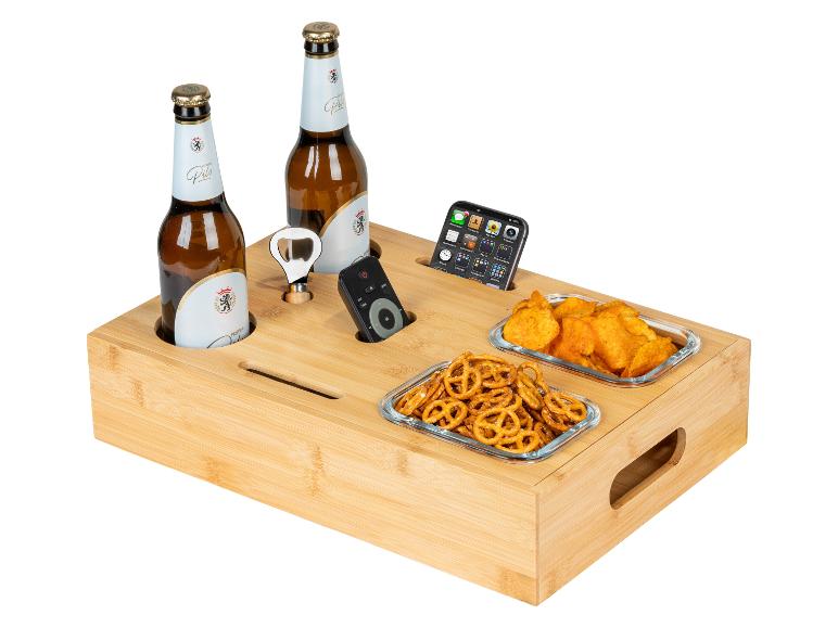Bamboe serveerblad met bierflessen, snacks, flesopener, afstandsbediening en telefoon.