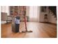 Dweil en emmer met wringsysteem in een woonkamer met houten vloer.