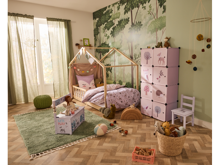 Kinderkamer met huisbed, roze opbergrekken en een vloerkleed.