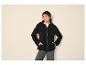 Vrouw in zwarte fleece hoodie, zwarte muts en donkere jeans.