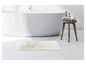 Een witte badkamermat voor de badkamer, naast een badkuip en een houten stoel.