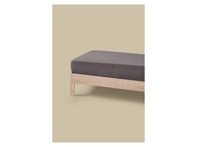 Een bed met een licht houten frame en een donkergrijs matras.