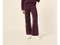 Vrouw in bordeauxrode gebreide flared broek en witte sneakers.