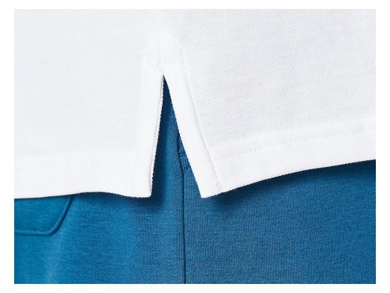 Wit poloshirt met een split aan de onderkant, gedragen over een blauwe broek.