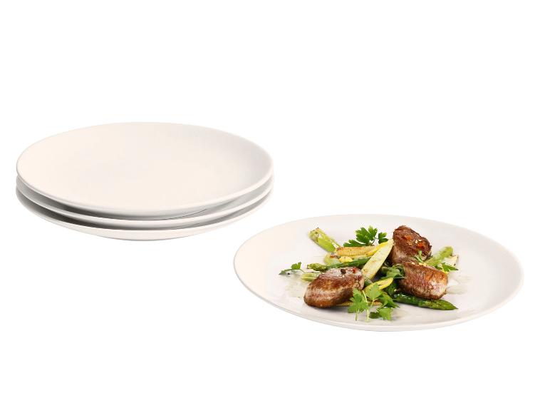 Gestapelde witte borden en een bord met ossenhaas, asperges en babymaïs.