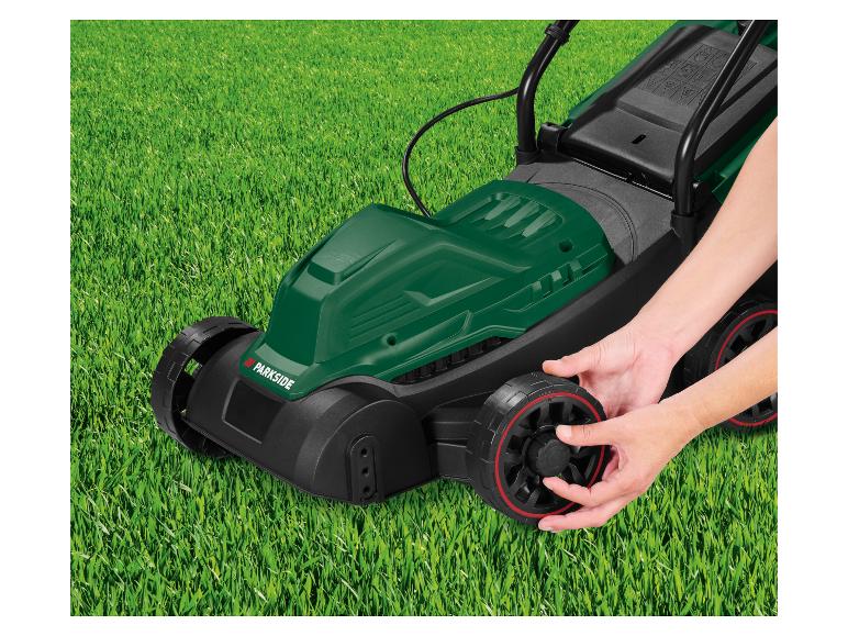 Groene Parkside grasmaaier op gras, handen stellen wiel af.