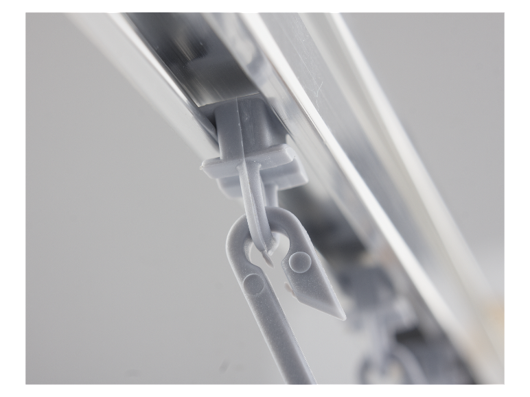 Close-up van grijze gordijnbevestigingen bevestigd aan een aluminium rail.