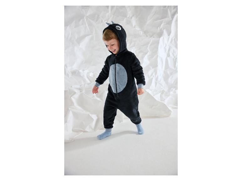 Lachende jongen in een zwarte pluchen onesie met grijze details.