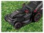 Elektrische grasmaaier met rode accenten op groen gras.