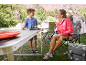 Vrouw en kind kamperen met een klaptafel, campingstoelen en tenten.