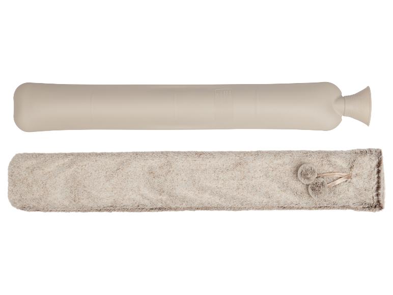 Een lange beige kruik en een pluizige beige hoes met pompons.