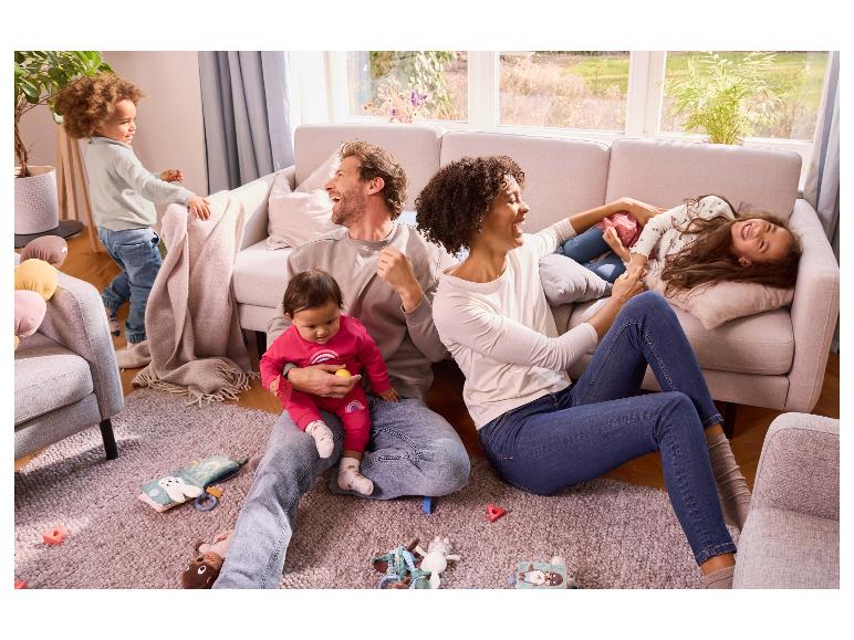 Een gezin speelt thuis, omringd door baby speelgoed.