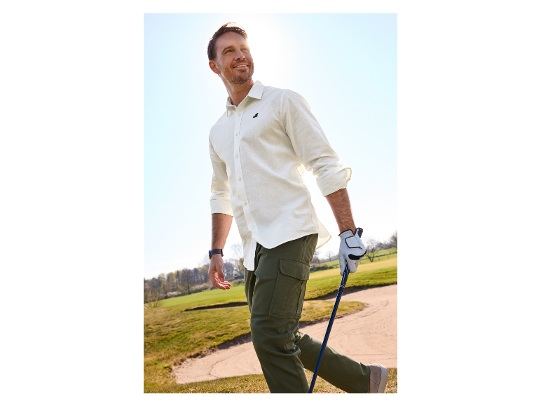 Man speelt golf in een wit overhemd en cargoshort.