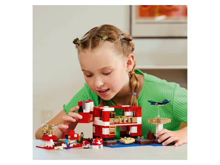 Meisje speelt met bouwstenen, bouwt een rood huis en dierenfiguren.