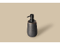 Donkergrijze keramische zeepdispenser met zwarte pomp op een lichtbeige achtergrond.