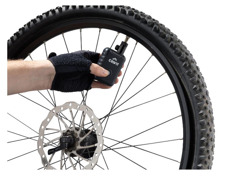 Gehandschoende hand pompt een Crivit fietsband op met een digitale luchtpomp.