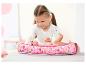 Meisje speelt met een BABY born pop in een roze stoffen wiegje met prints.