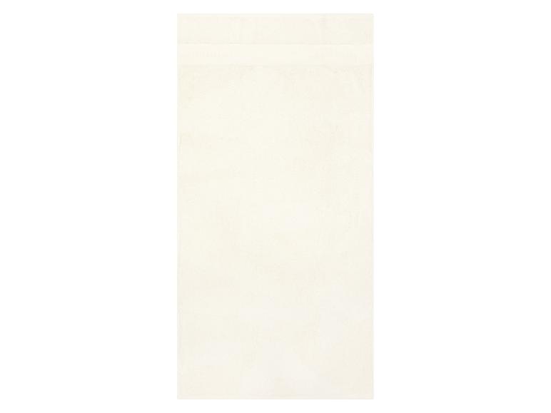 Een effen crèmekleurige badhanddoek met een subtiele getextureerde band bovenaan.