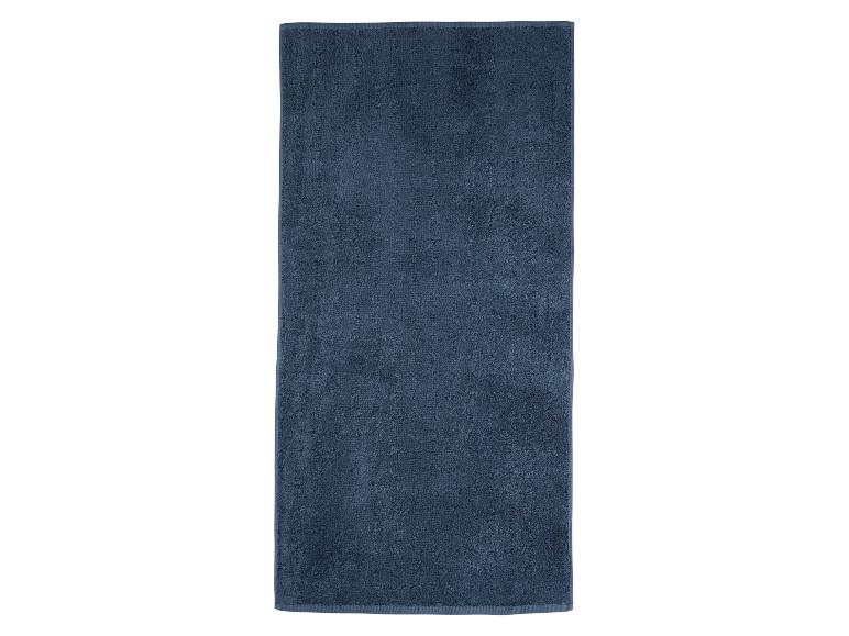 Een donkerblauwe badhanddoek gevouwen op een witte achtergrond.