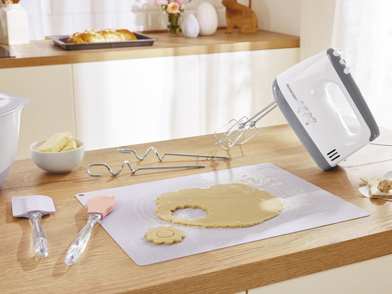Een handmixer van Silvercrest, deeg op een bakmat en bakgerei.