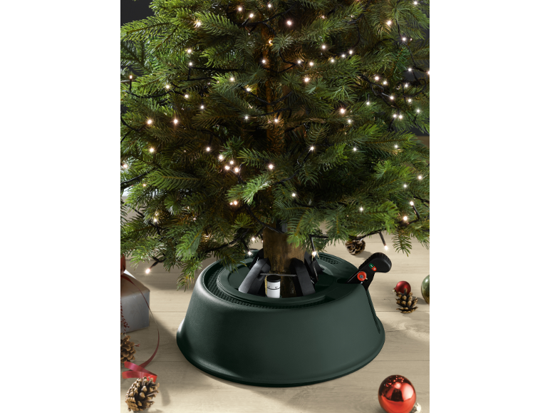 Verlichte kunstkerstboom met groene voet en feestelijke decoraties.