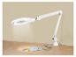 Witte vergrootlamp met naaibenodigdheden op een houten tafel.