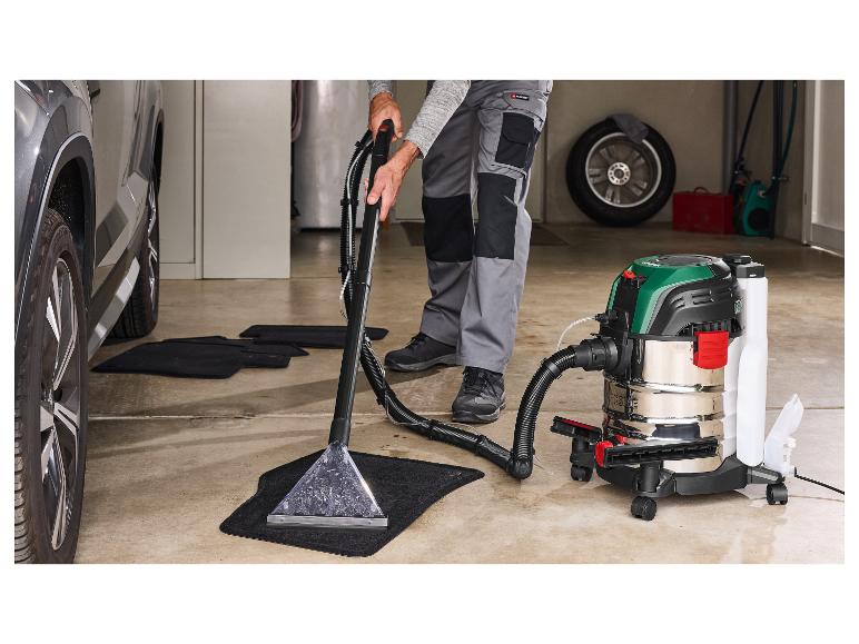 Man reinigt automatten met een Parkside stofzuiger in een garage.