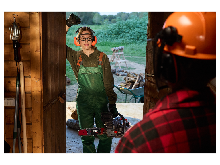 Een vrouw met een Parkside kettingzaag in een houten schuur.