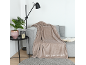Gezellige woonkamer met een grijze bank, een beige plaid en een vloerlamp.