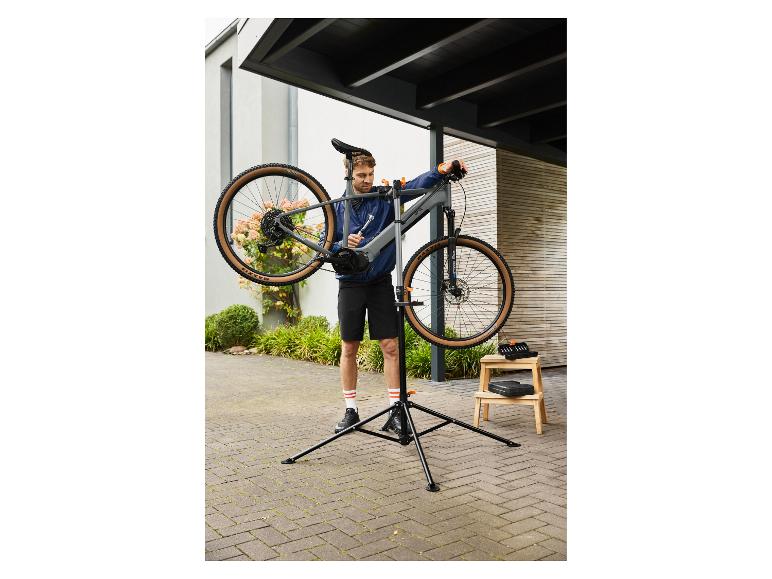 Man repareert een fiets op een fietsreparatiestandaard buiten.