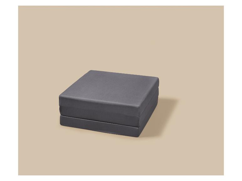 Opvouwbaar grijs matras op een beige achtergrond.