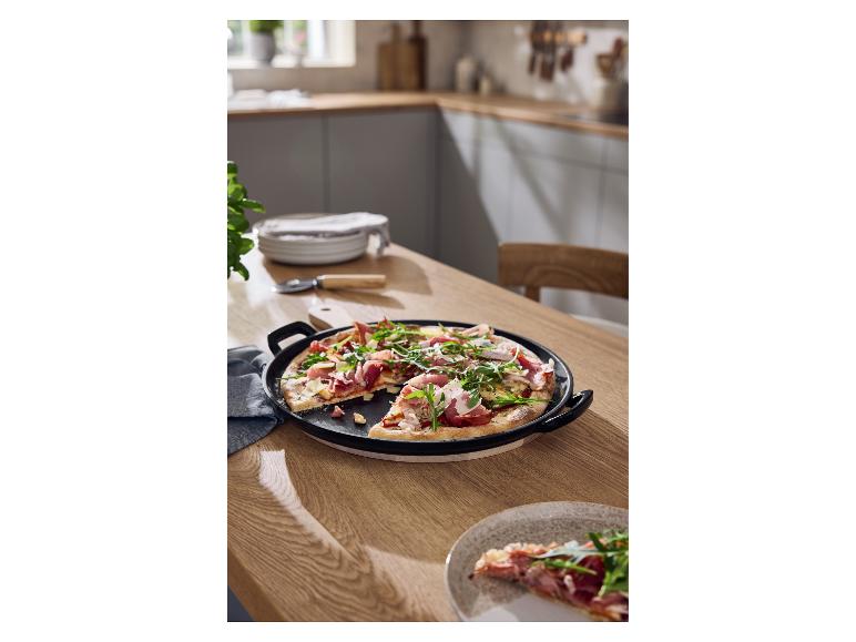 SILVERCREST® gietijzeren pizzaplaat met een vers gebakken pizza op een houten tafel