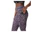 Vrouw in sportbeha en legging met luipaardprint, telefoon in zijzak.