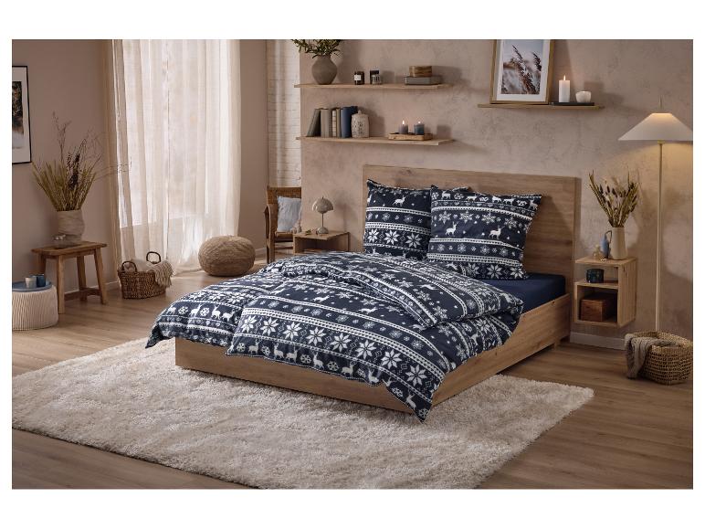 Beddengoed met rendier- en sneeuwvlokkenpatroon op een houten bed in een gezellige slaapkamer.