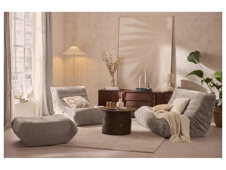 Woonkamer met twee grijze fauteuils, een poef, een salontafel en een dressoir met decoraties.