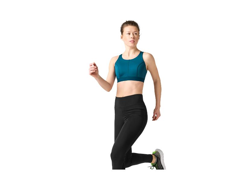 Vrouw in zwarte legging en teal sportbeha, rennend.
