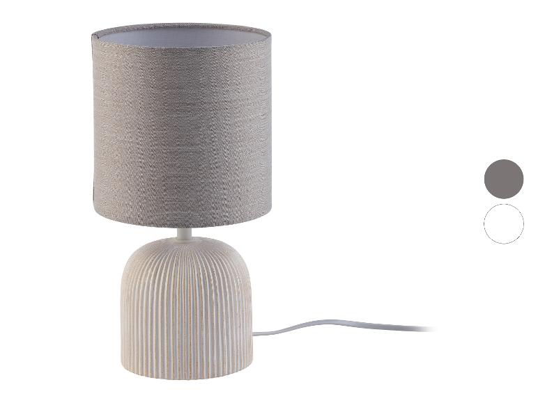 Beige tafellamp met linnen lampenkap en geribde keramische voet.